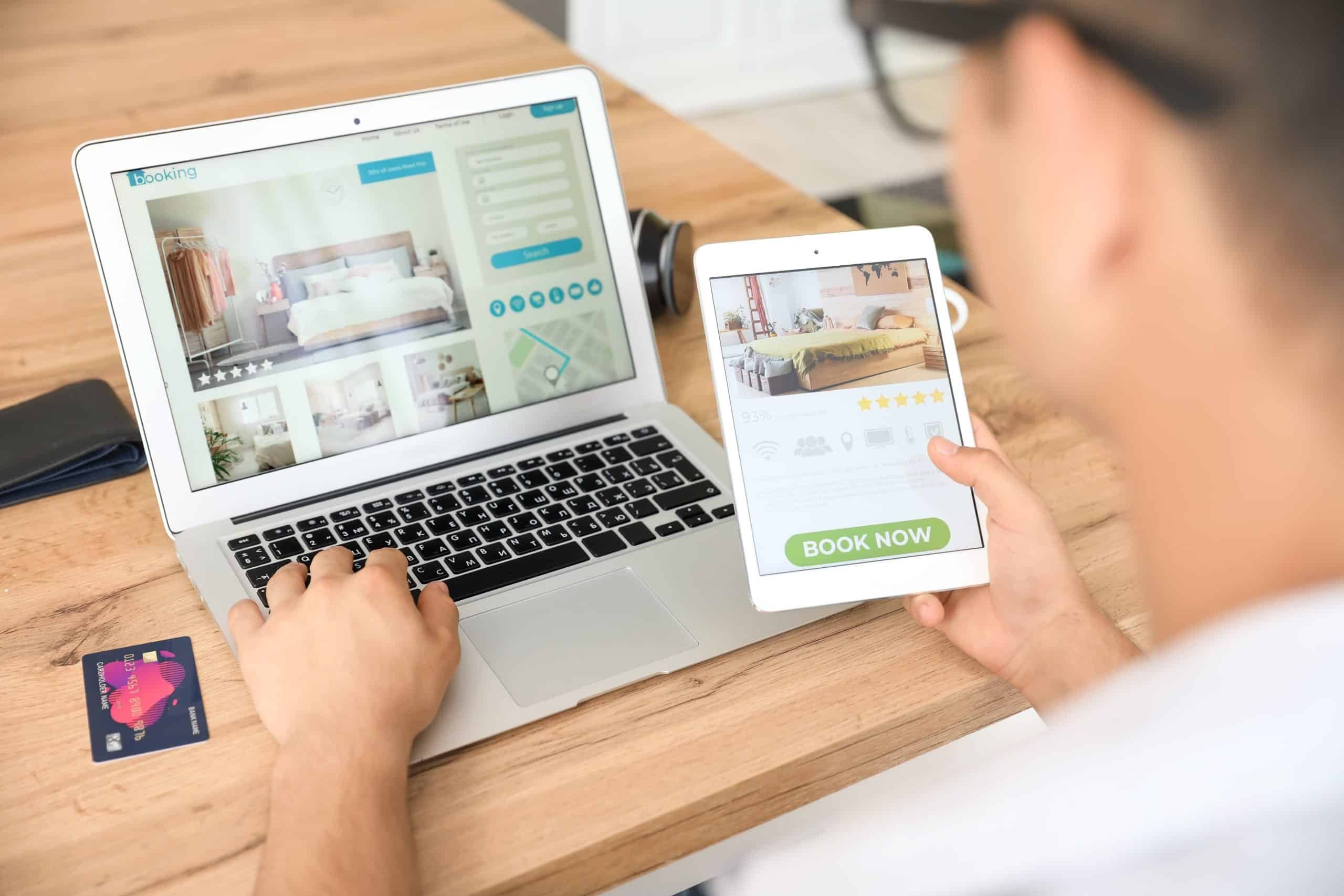 Man with tablet computer booking room in hotel online at home